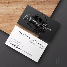 two black and white business cards sitting on top of a wooden table