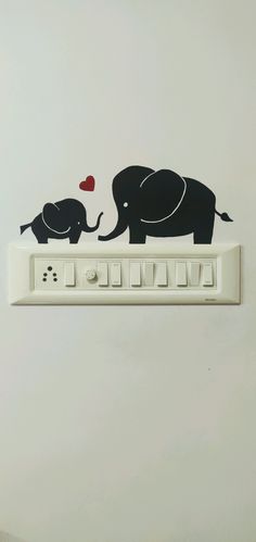 an elephant and baby elephant on top of a switch box with a red heart in the middle