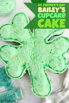 a shamrock shaped cake with green frosting and sprinkles on the side