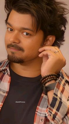 a close up of a person with a watch on his wrist and wearing a plaid shirt