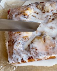 a person cutting into a cake with a knife on top of it and covered in icing