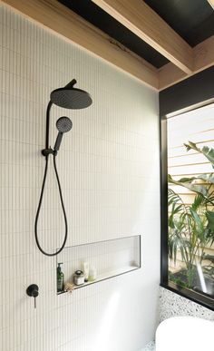 a bathroom with a shower head and hand held shower faucet next to a window