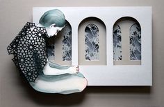 a paper sculpture of a woman sitting in front of a window