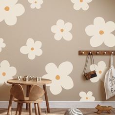 a wall with flowers painted on it next to a wooden table and chair in front of the wall