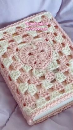 a pink crocheted book cover sitting on top of a bed