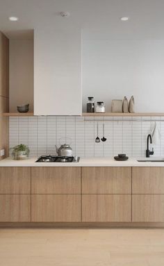 a kitchen with wooden cabinets and white tile backsplashing, pots on the stove