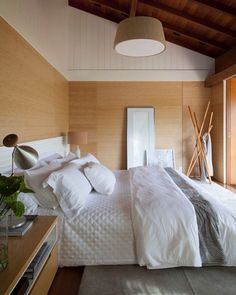 a large bed sitting in a bedroom next to a wooden ceiling mounted light above it