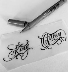 a pen sitting on top of a piece of paper with the word queen written in cursive writing