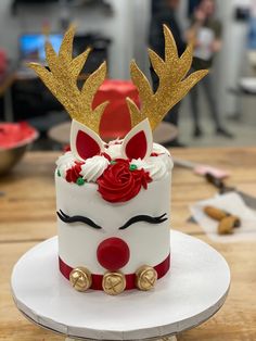 a decorated cake with gold antlers and red roses on the top is sitting on a white plate