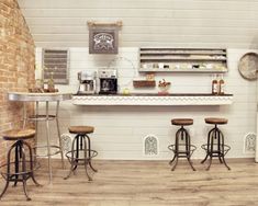 an old fashioned bar with four stools in front of it and a brick wall