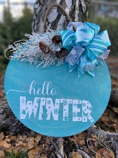 a wooden sign that says hello winter with pine cones and snowflakes on it