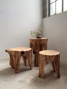 three wooden stools sitting next to each other in front of a window with a potted plant on top