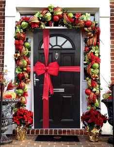 a black door with red ribbon and poinsettis