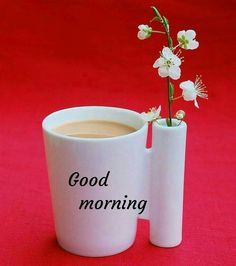 two white cups with flowers in them sitting on a red surface that says good morning