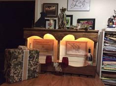 a wooden table topped with lots of boxes next to a shelf filled with folded paper