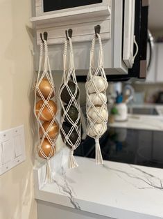 three macaroons hanging from hooks on a kitchen wall