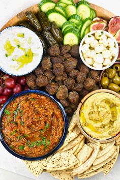 a platter filled with different types of food and dips on top of crackers