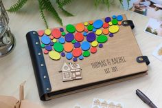 a personalized wooden notebook with colorful balloons on the cover, surrounded by other items