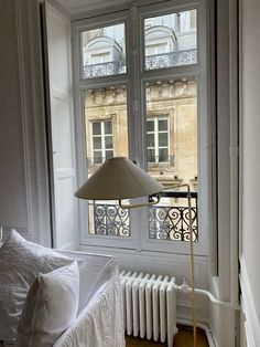 the lamp is next to the bed in the room with the large window on the side