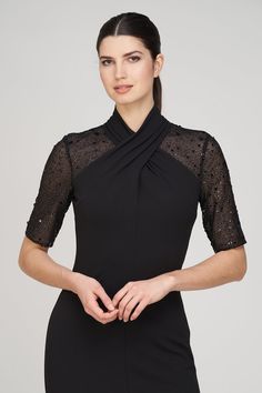 a woman is wearing a black dress with sheer sleeves and an asymmetrical neckline