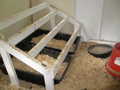 an animal pen with hay in it next to a red bucket