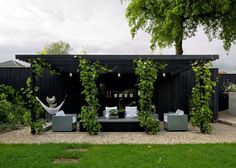 an image of a black house with vines growing on the roof and windows above it