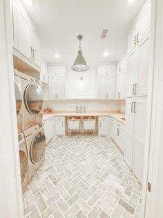 an empty laundry room with white cabinets and tile flooring, including a washer and dryer