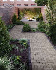 an outdoor courtyard with brick pavers walkways and plants on either side, surrounded by greenery