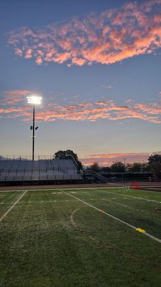 the sun is setting over an empty soccer field