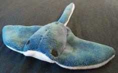 a blue and white stuffed animal laying on top of a black bed cover covered in sheets