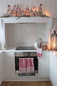 a kitchen with white cabinets and pink rugs on the counter top, along with christmas lights