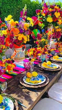 the table is set with colorful flowers and plates