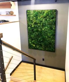 a green wall mounted to the side of a white wall next to a stair case