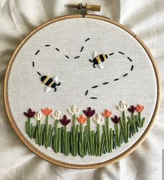 a close up of a embroidery on a piece of cloth with flowers and a bee