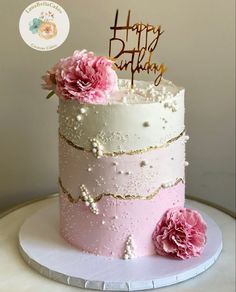 a pink and white birthday cake with flowers on top