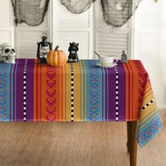 a colorful table cloth with skulls and pumpkins on it, sitting in front of a window