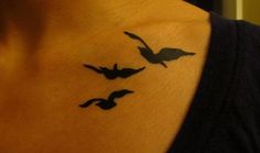 a woman's chest with three birds on it and one bird flying in the air