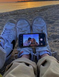 someone is taking a photo with their cell phone on the beach while they are laying down