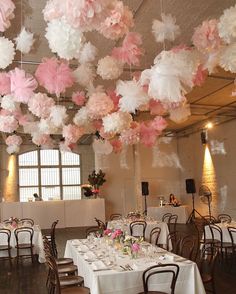 a dining room filled with lots of tables covered in pink and white paper flowers