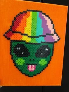 someone is holding up a piece of art made to look like a skull with a rainbow hat