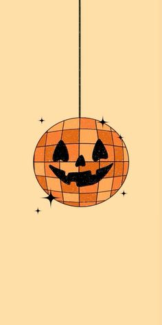 an orange and black pumpkin hanging from a metal hook on a yellow background with stars