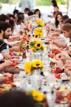 a group of people sitting at a long table eating food