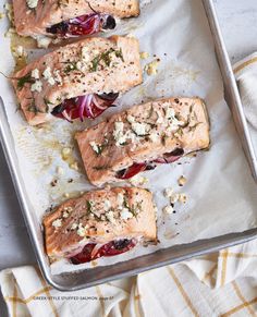 four salmon fillets with cranberry sauce and herbs on a baking sheet, ready to go into the oven