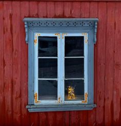 a red building with two windows and a yellow vase on the window sill in front of it