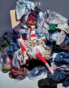 a woman sitting on top of a pile of clothes