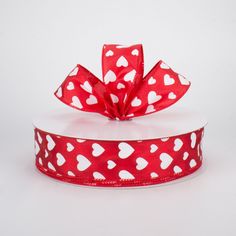 a red ribbon with white hearts on it and a bow at the top that is tied in two different ways