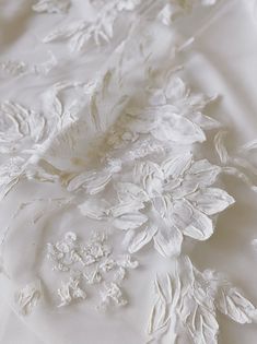 close up view of white fabric with flowers and leaves on the bottom half of it