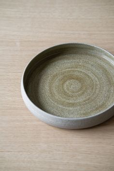 a small white bowl sitting on top of a wooden table next to a black object