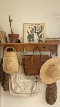 hats and purses are hanging on the wall in front of a shelf with books