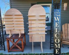 two wooden chairs sitting next to each other on a porch near a welcome sign that says welcome